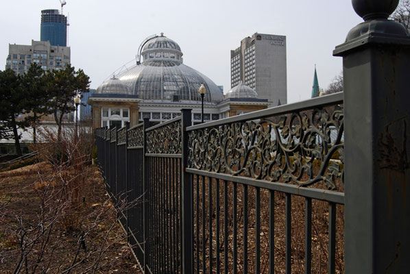 looking across a wrought iron fence towards the dome of the Palm House