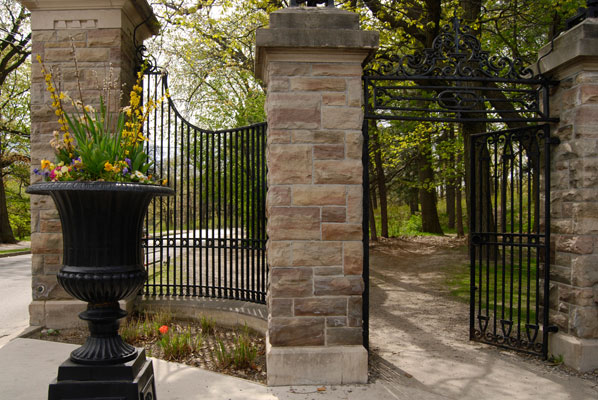 a huge urn of flowers stands infront of the wrought iron gates to High Park