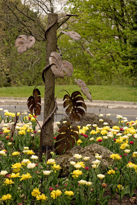 a metal sculpture of vine leaves in the centre of a garden bed