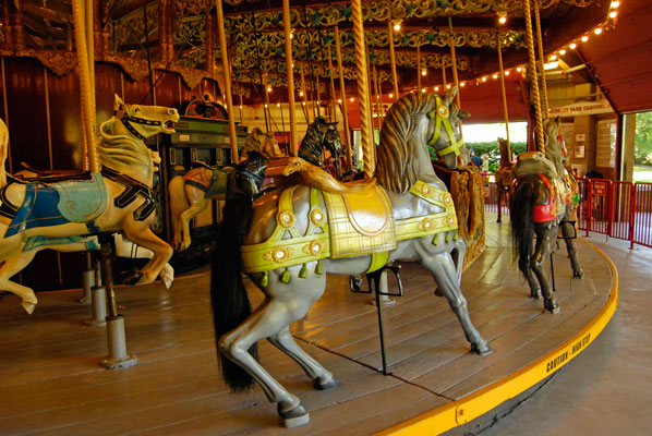 a grey carousel horse with a yellow saddle