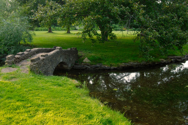 a stone bridge crosses a pond