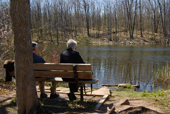 two people seated on a bench with a view of the lake